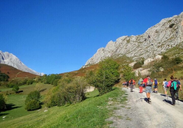 The hikers walking through a pathway surrounded by hills covered in greenery under the sunlight at daytime